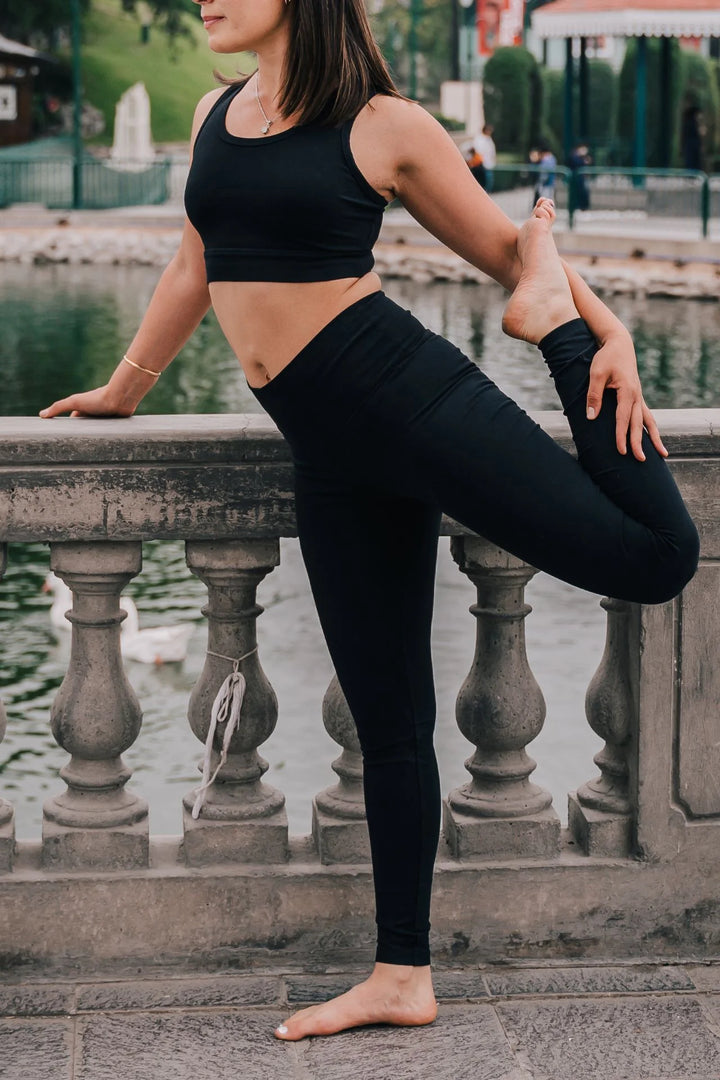 Woman stretching outdoors in black organic cotton leggings 28"