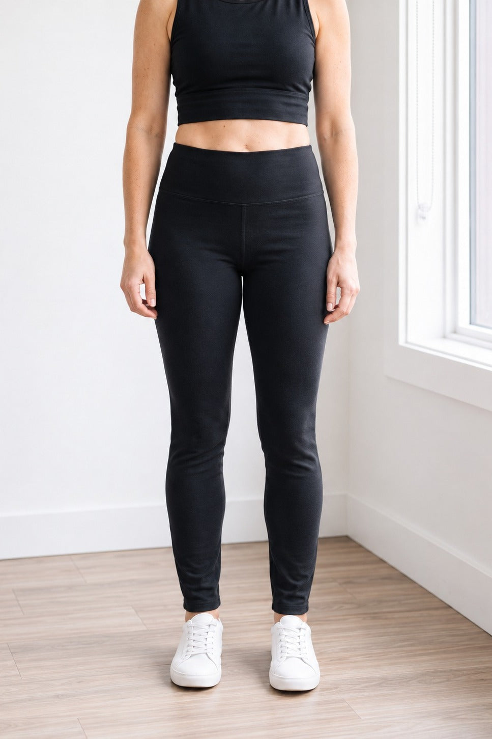 Front view of black organic cotton leggings with 27" inseam (Regular length) hitting at the ankle, high-rise waistband