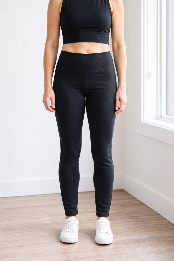 Front view of black organic cotton leggings with 27" inseam (Regular length) hitting at the ankle, high-rise waistband