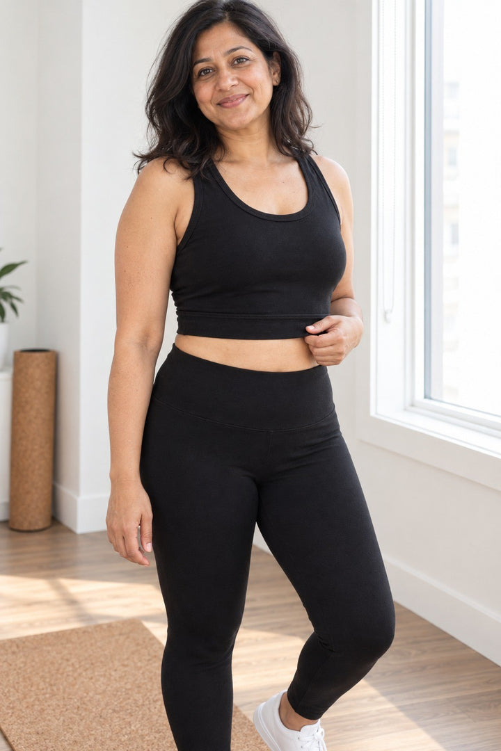 Black organic cotton tank-length crop top with wide straps and scoop neckline, worn with high-waisted leggings