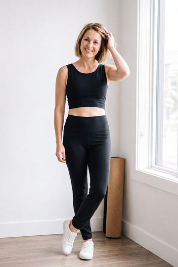 Woman wearing black organic cotton leggings 27" inseam (Regular length) and black organic cotton bra tank top, full body front